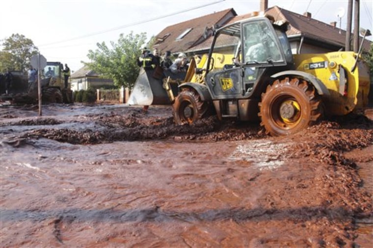 Local residents are rescued by excavators in Devecser, 164 kilometers southwest of Budapest, Hungary on Monday. Rescue services say the reservoir of an alumina plant in western Hungary has burst, flooding several towns including Devecser with red sludge. 